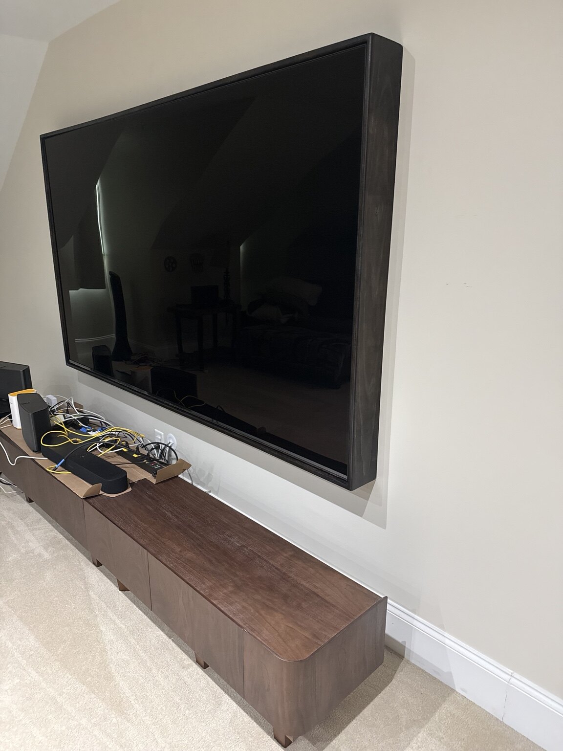 Custom dark wood frame around a wall-mounted television with matching media cabinet